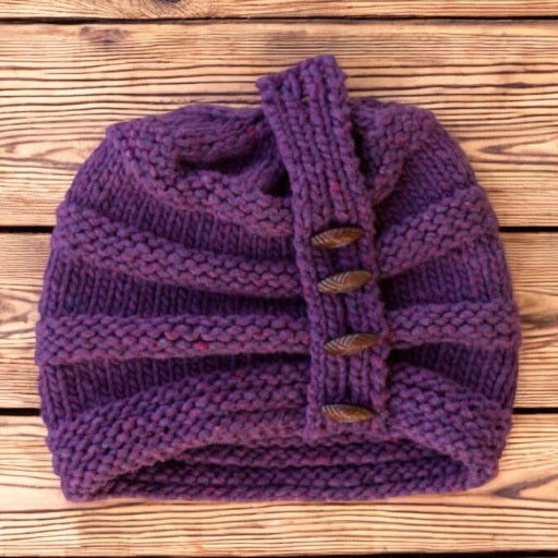 Charlotte Rose Hat in Elderberry laid flat on wood, showing the buttoned band