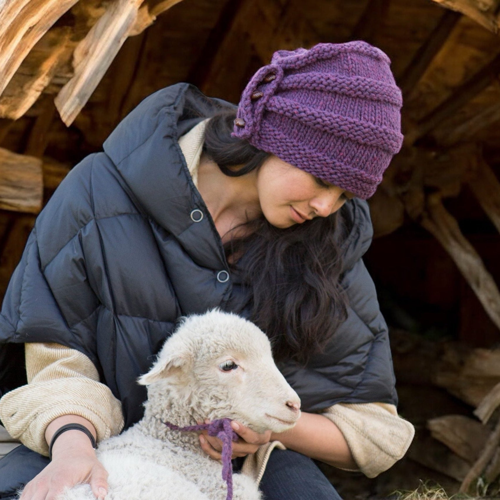 Charlotte Rose Hat in Elderberry alpaca/wool worn while holding a lamb